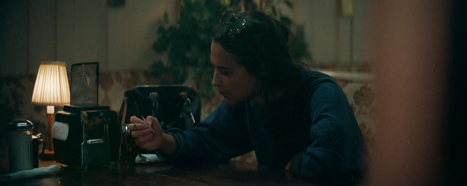 a woman sitting at a table looking at her cell phone