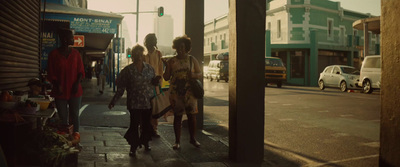 a group of people walking down a street next to tall buildings