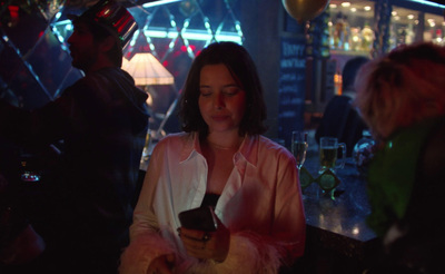 a woman sitting at a bar looking at her cell phone