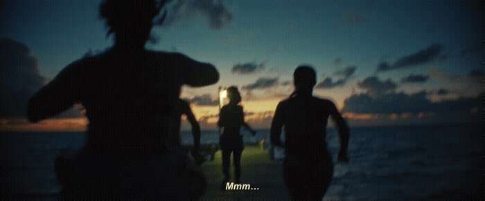 a group of people walking along a beach at night