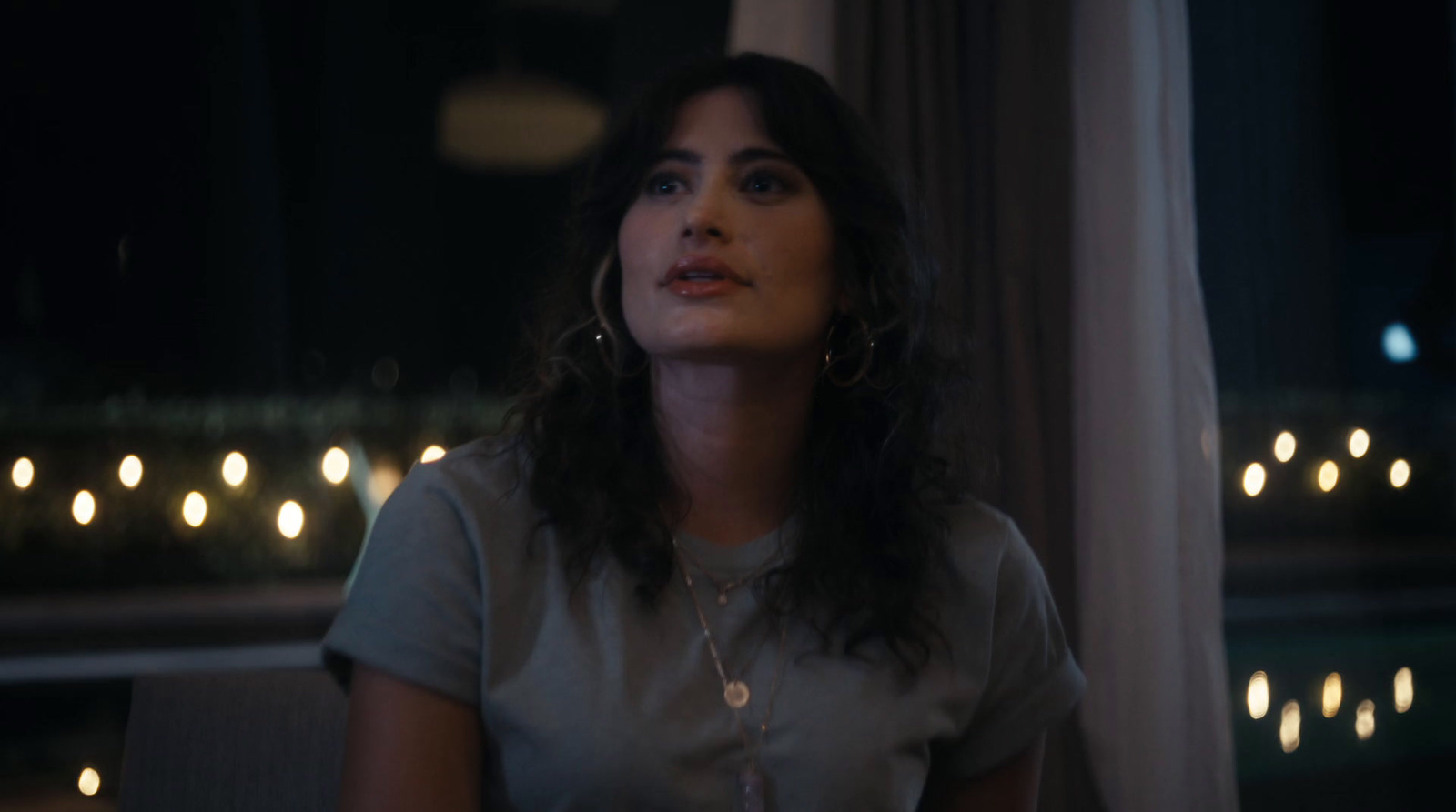 a woman sitting in front of a window at night