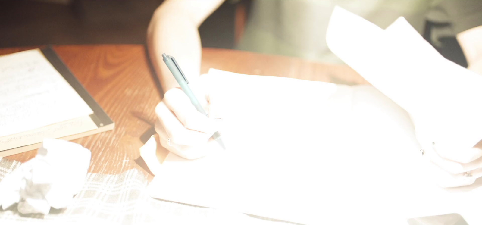 a person sitting at a table with papers and a pen