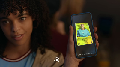 a woman holding up a cell phone with a picture of a man on it