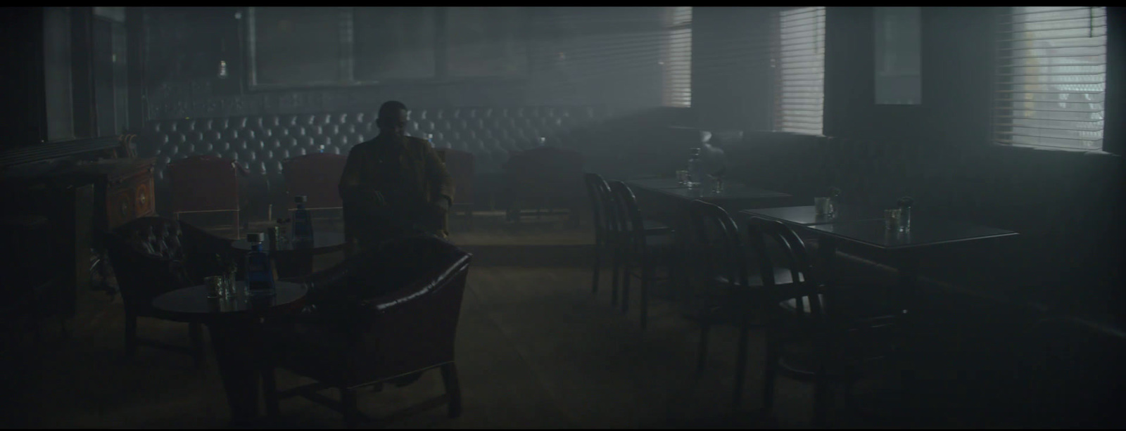 a person standing in a dark room with a table and chairs