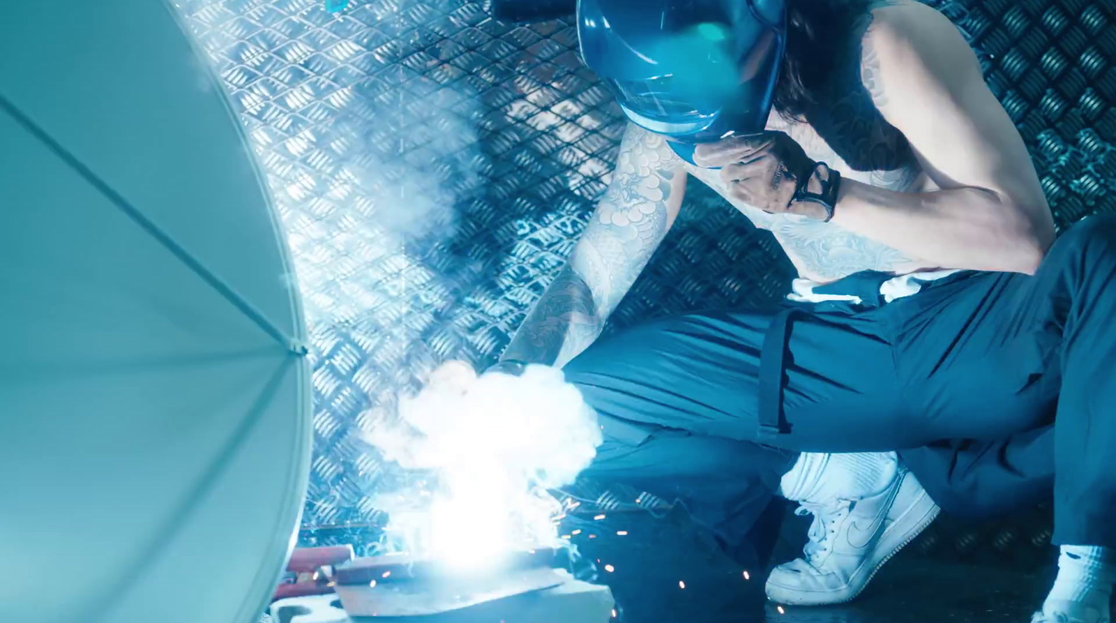 a man in a blue suit and helmet welding a piece of metal