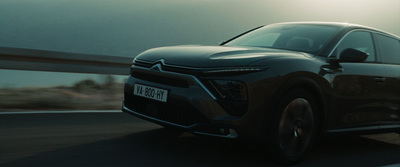 a black car driving down a road next to a bridge