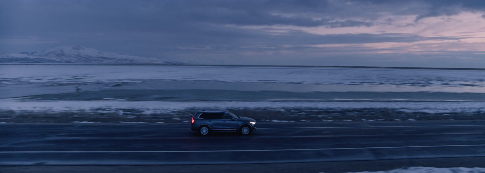 a car driving down a road next to a large body of water