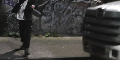 a man riding a skateboard down a street next to a graffiti covered wall