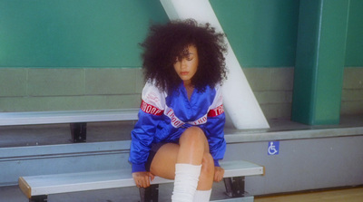 a woman sitting on a bench wearing a blue jacket and white socks