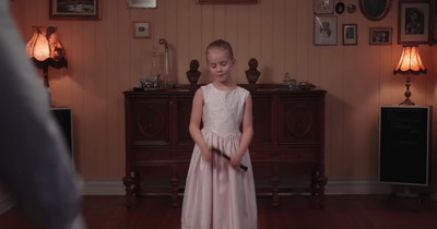 a little girl in a dress standing in a room