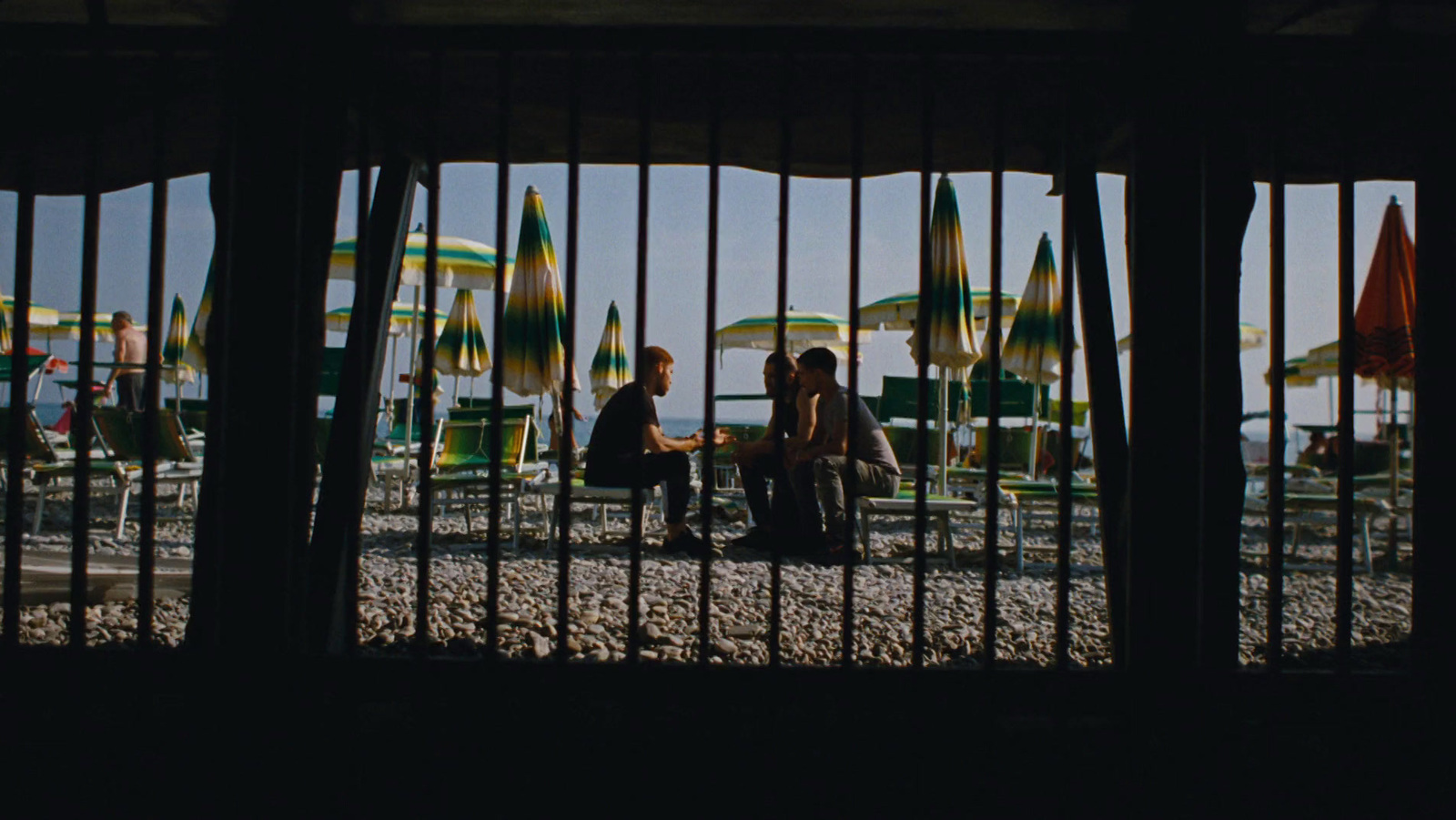 a group of people sitting on a bench in front of umbrellas