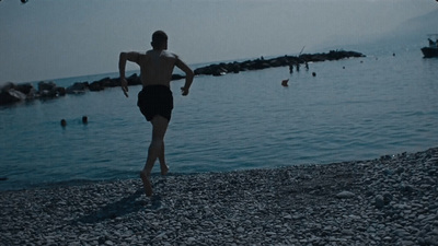 a man walking on a beach next to a body of water