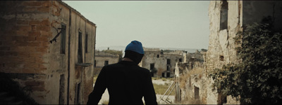 a man in a blue hat walking down a street