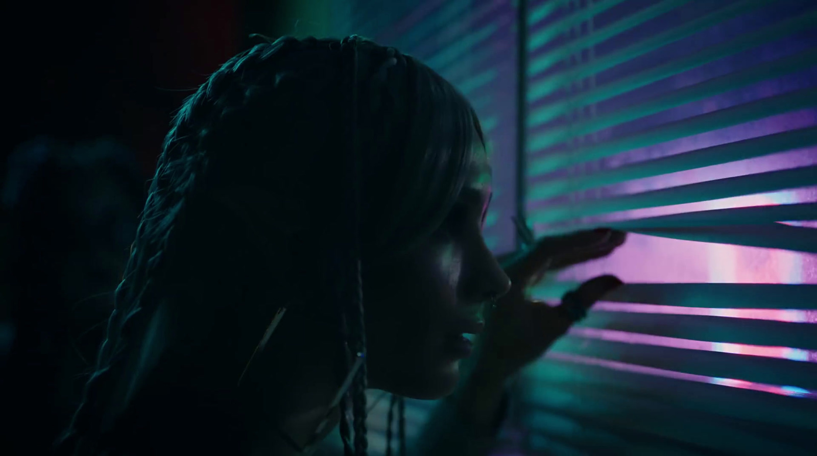 a woman standing next to a window covered in blinds