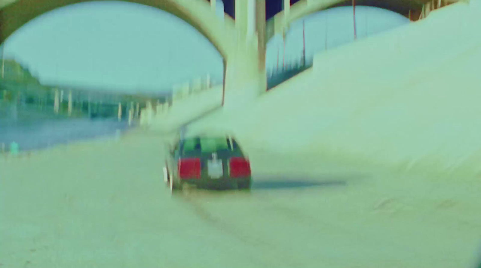 a car driving down a road under a bridge