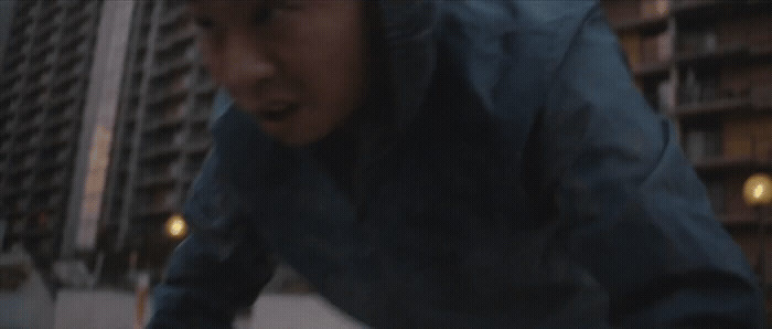 a man riding a skateboard down a street next to tall buildings