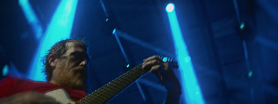 a man playing a guitar in front of blue lights