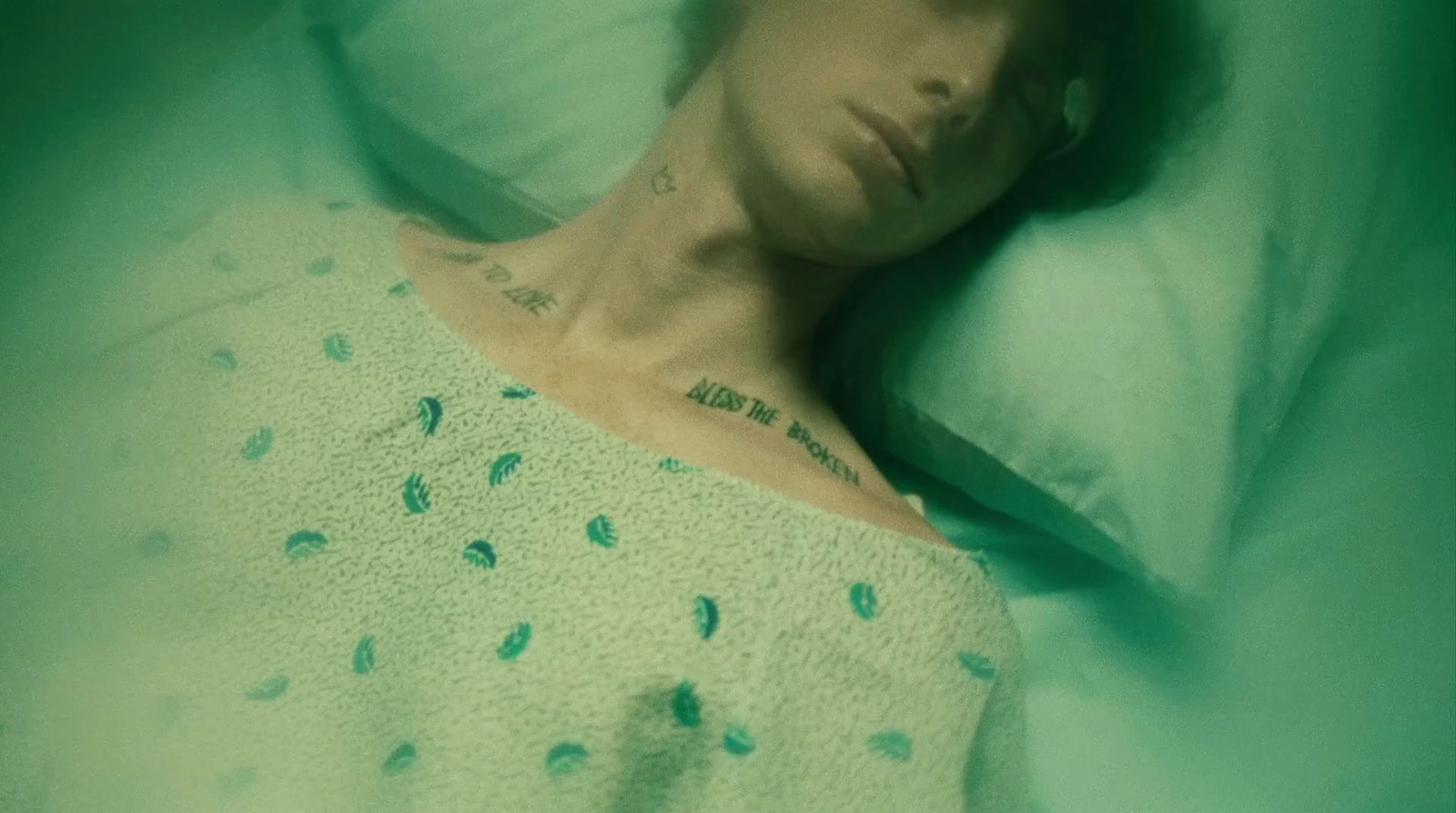 a woman laying in a bed with a tattoo on her chest