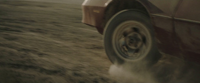 a red car driving down a dirt road