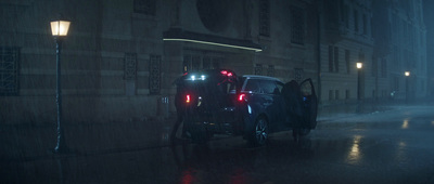 a couple of people standing next to a car in the rain