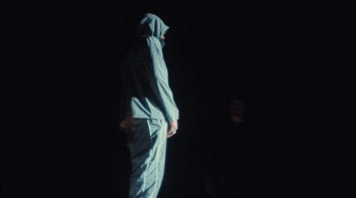 a man in a blue raincoat is standing in the dark