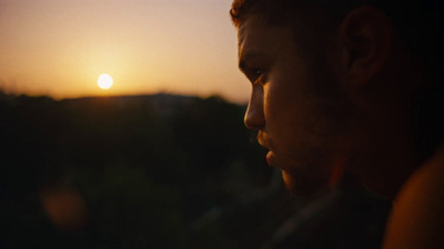 a man looking at his cell phone at sunset