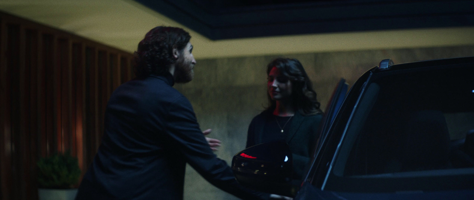 a man and a woman shaking hands in front of a car