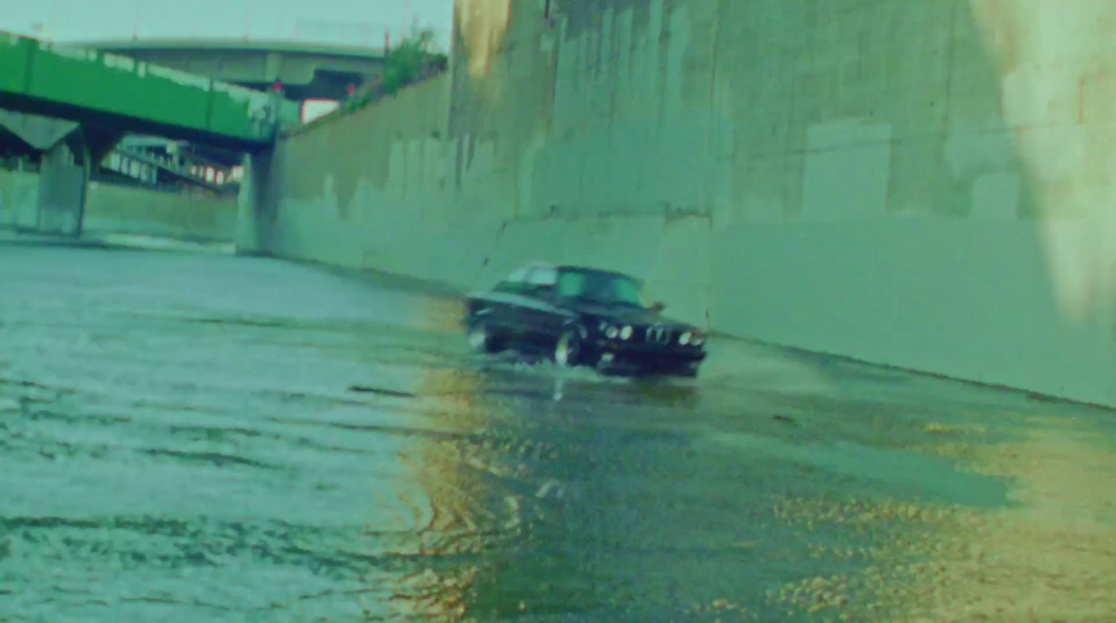 a black car driving down a flooded street