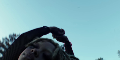 a man with dreadlocks standing in front of a blue sky