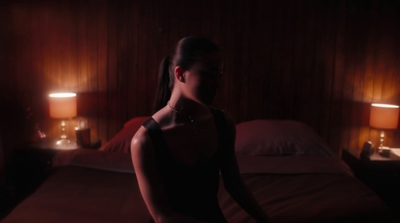 a woman standing in a dark room next to a bed