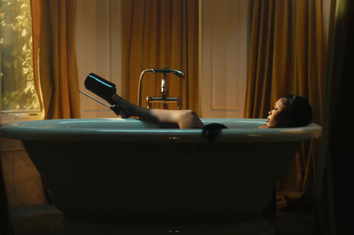 a woman laying in a bathtub with a hair dryer in her hand