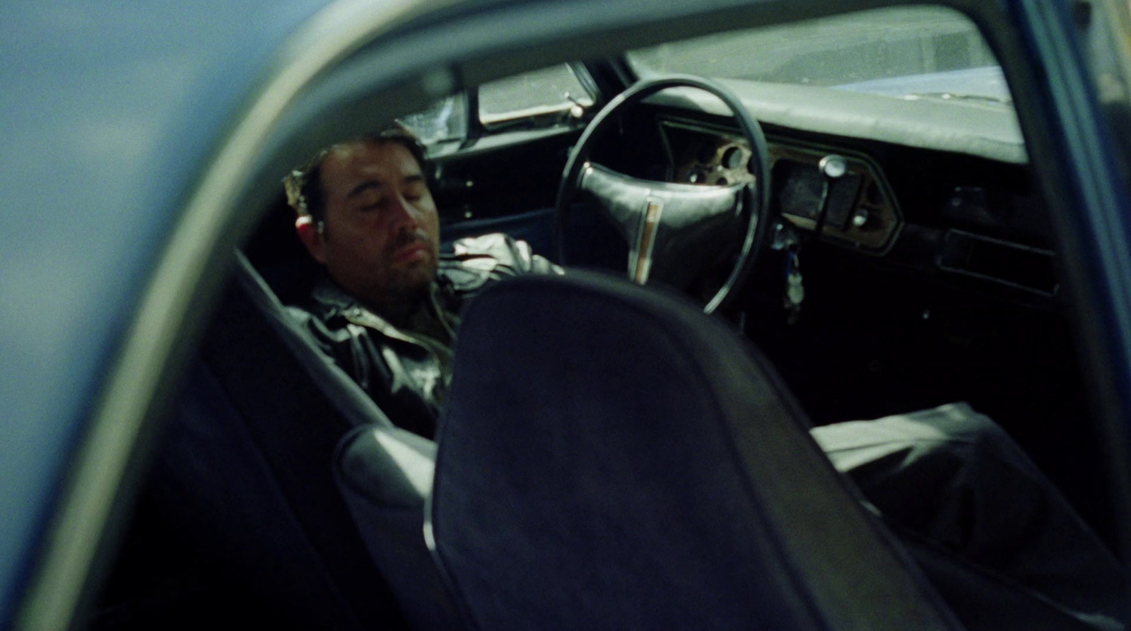 a man sitting in a car with a steering wheel