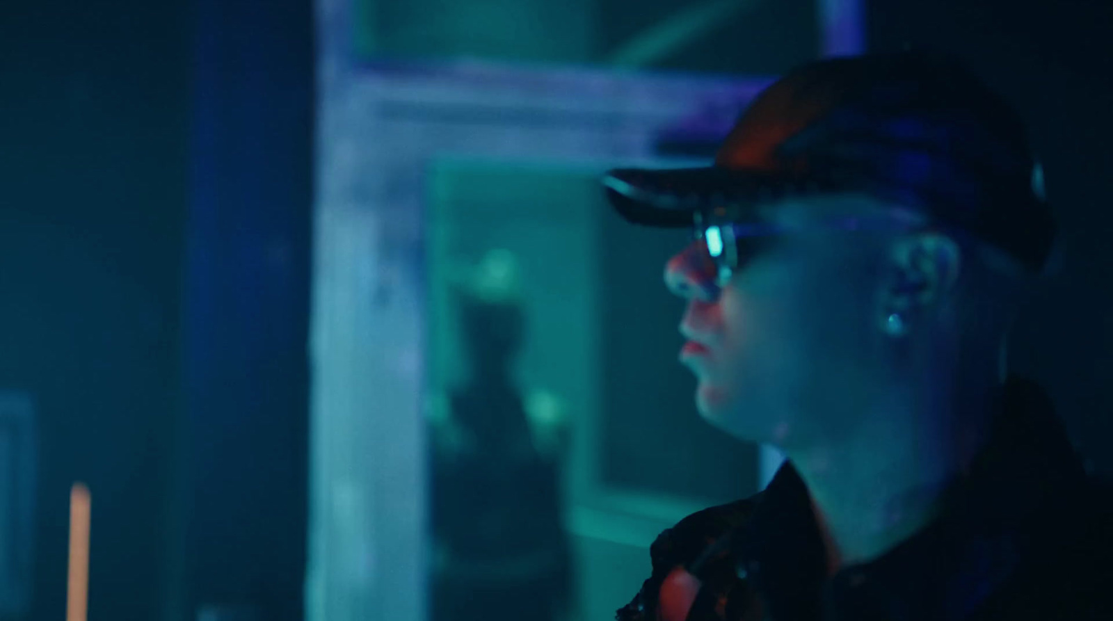 a man wearing a hat and glasses in a dark room