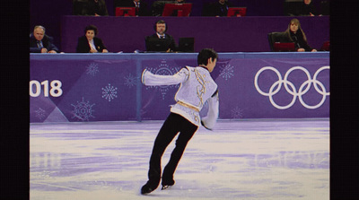 a man skating on an ice rink in front of a crowd