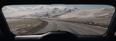 a view of a snowy mountain range from inside a vehicle