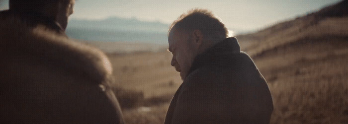 a man standing next to another man in a field