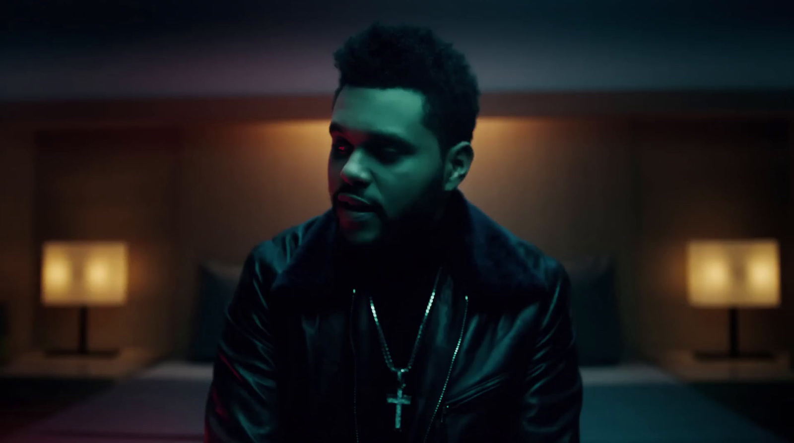 a man in a black leather jacket standing in a dimly lit room