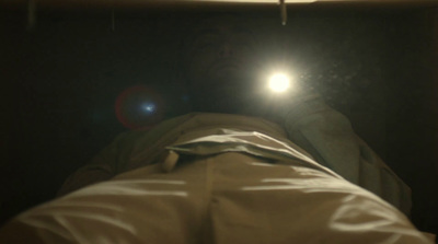 a person laying in a bed with a flashlight