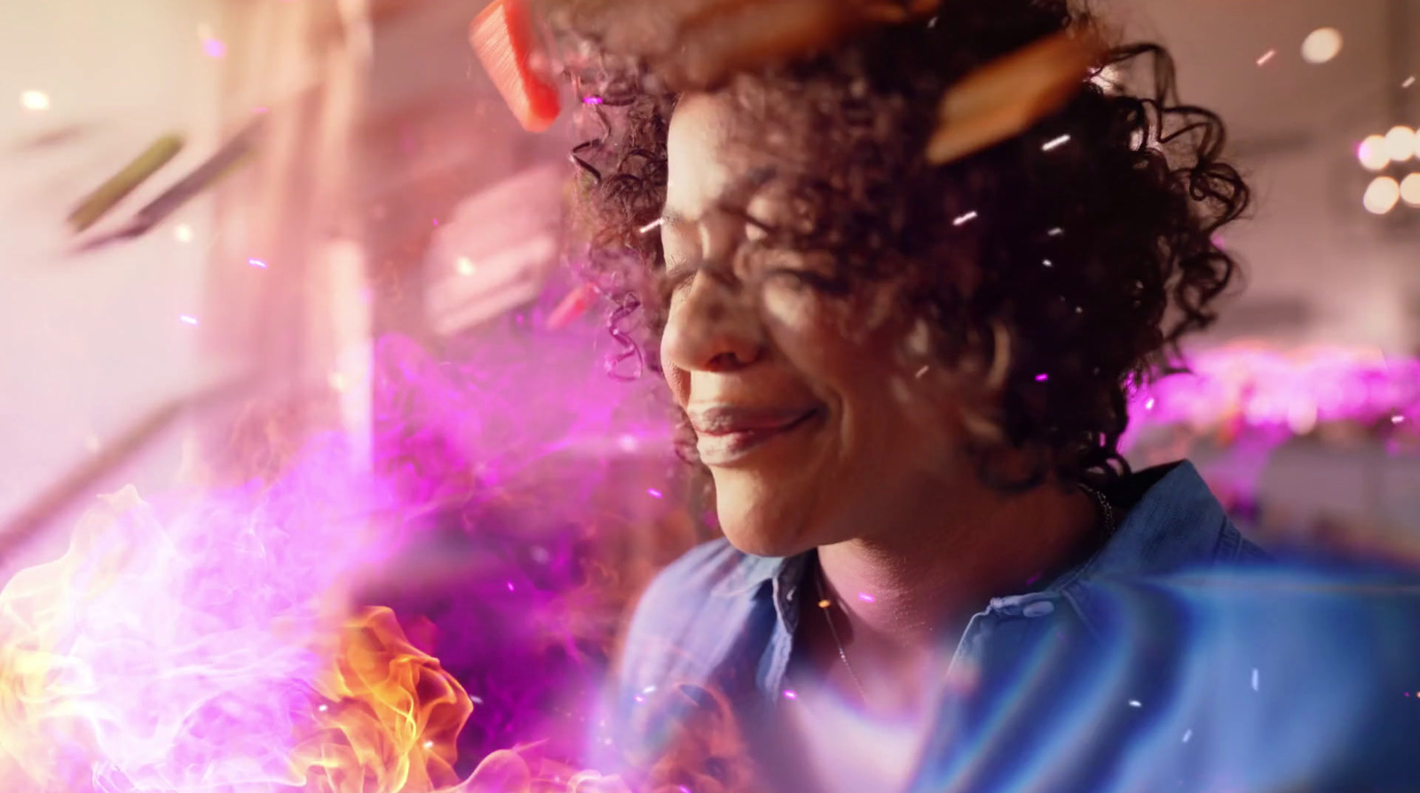 a woman with curly hair is smiling and holding a sparkler