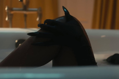 a woman's legs in a bathtub with black gloves on