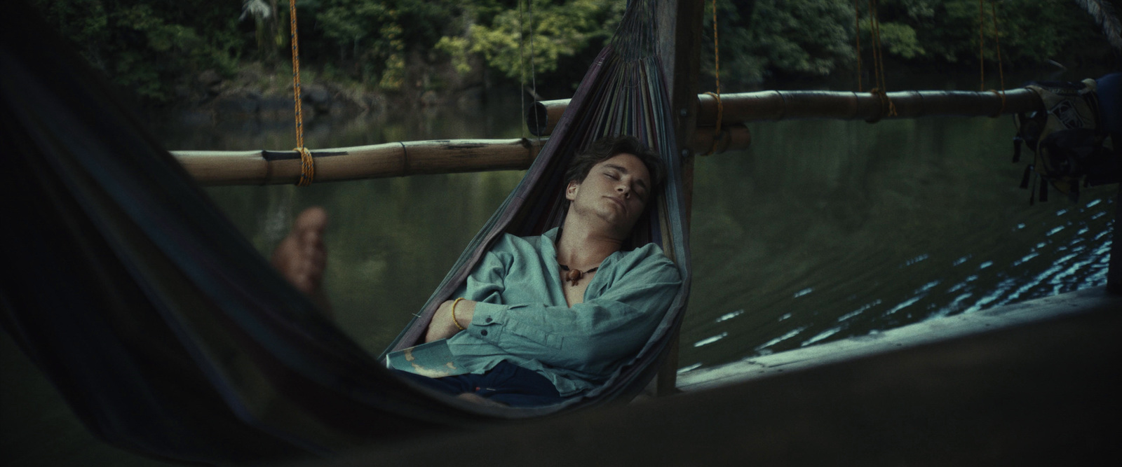 a man laying in a hammock on a river