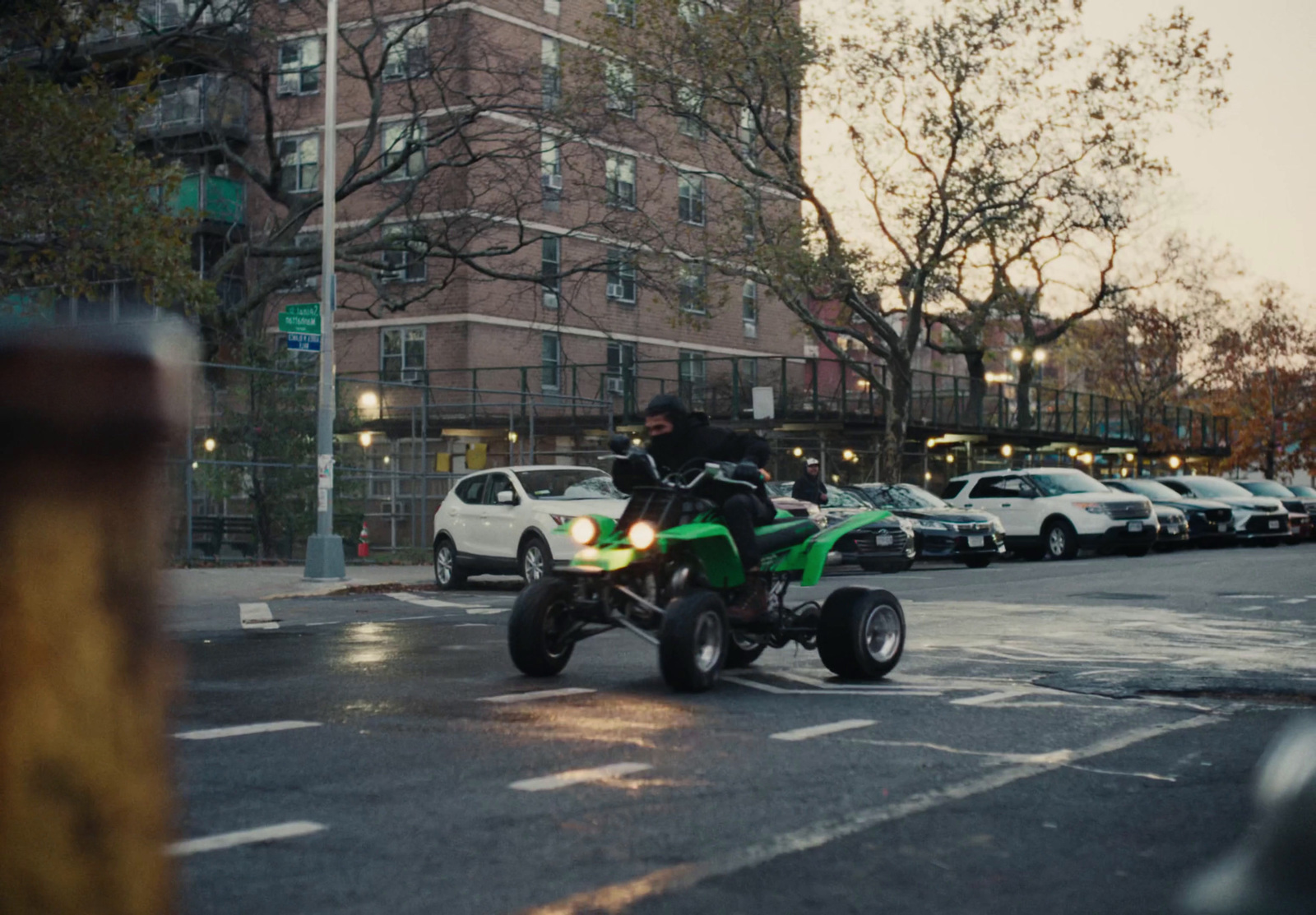 a man riding a green four wheeler on a city street