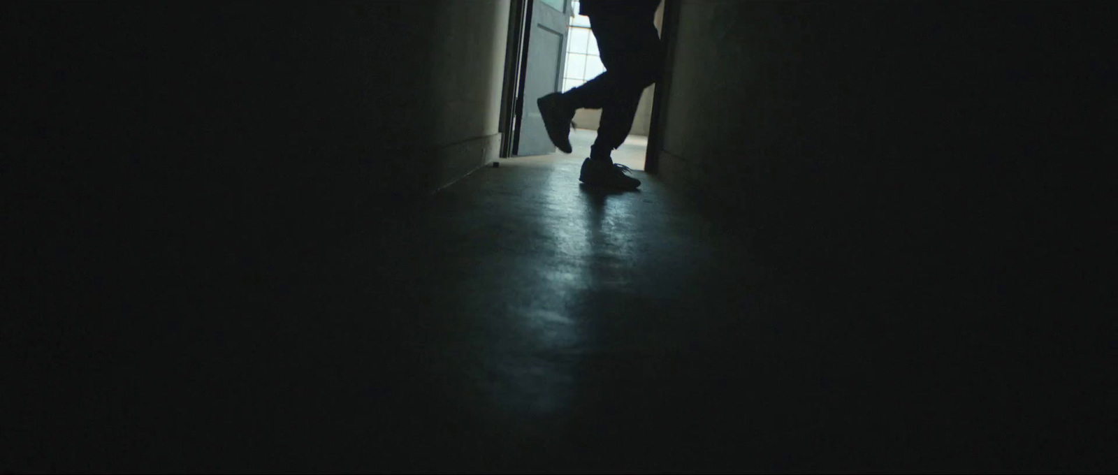 a person standing in a dark hallway with their feet up