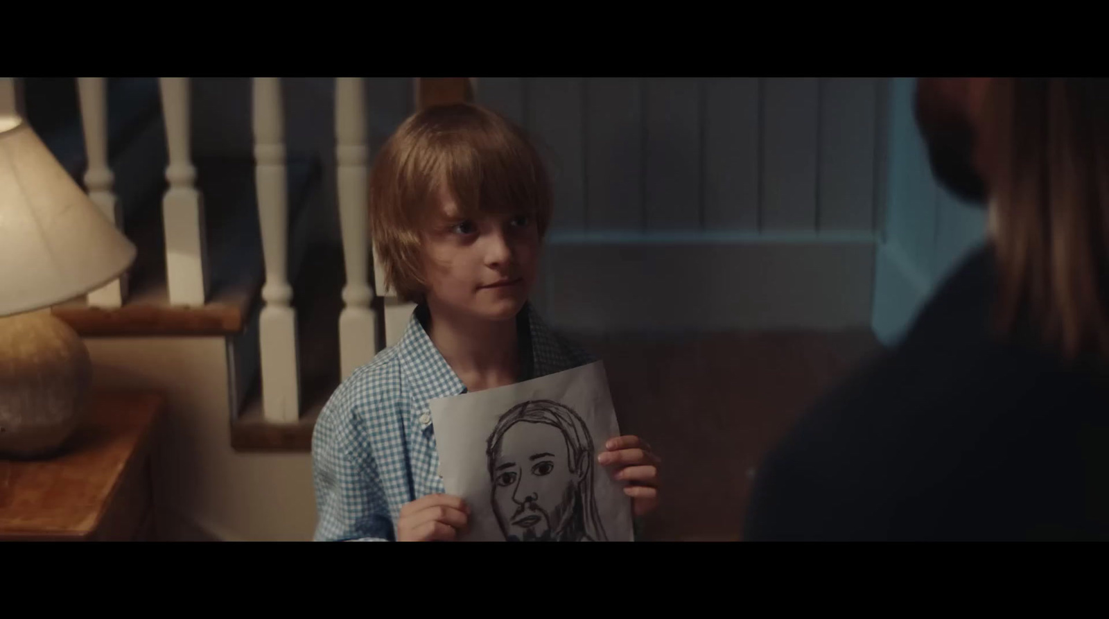 a young boy holding up a picture of himself