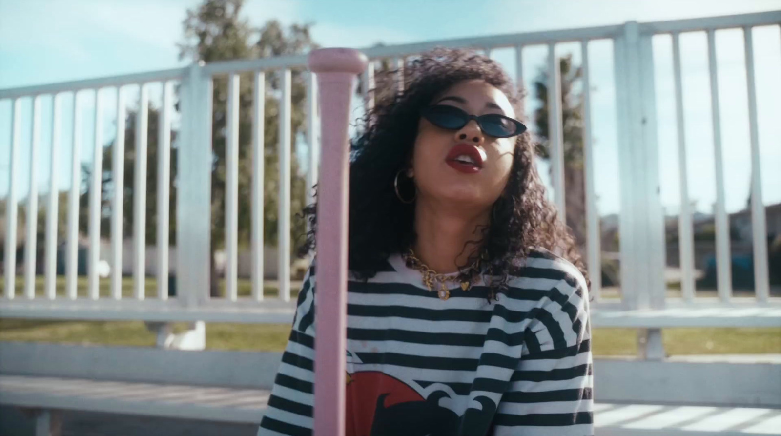 a woman wearing sunglasses standing next to a pink pole