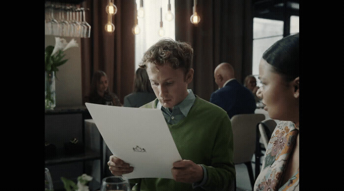 a man in a green sweater looking at a piece of paper