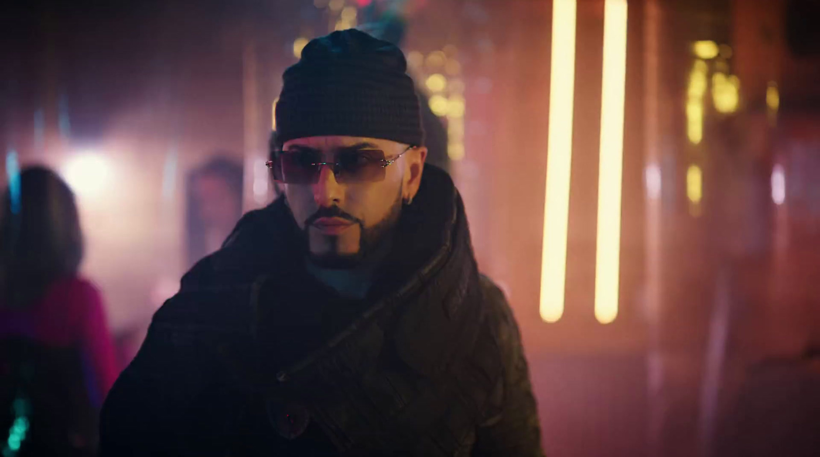 a man wearing sunglasses and a beanie in a dark room