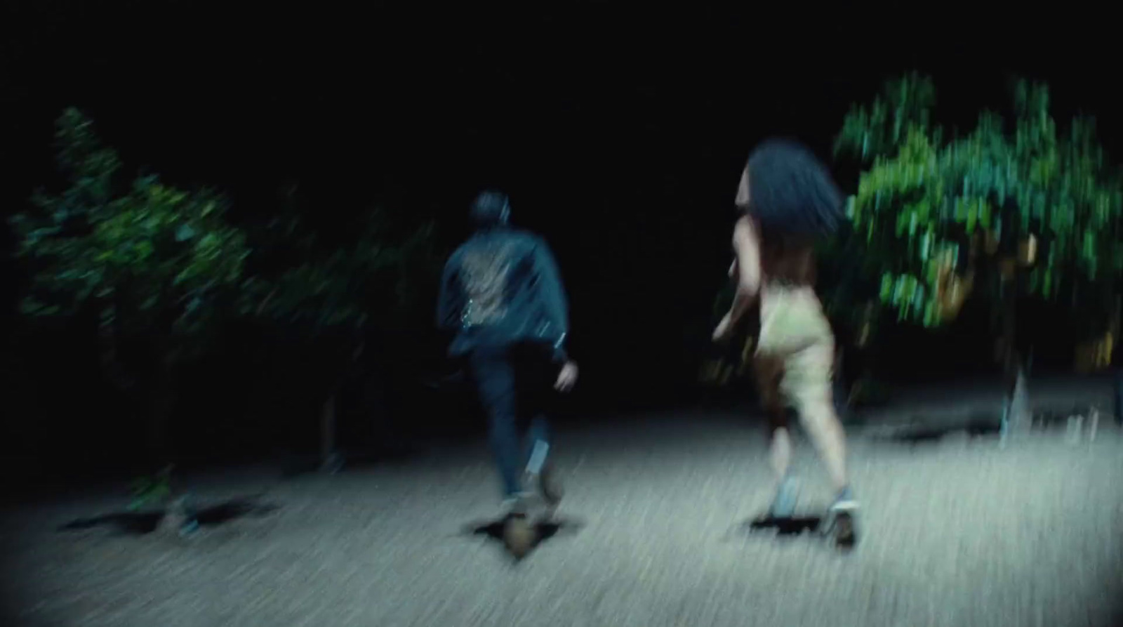 a man and a woman riding skateboards at night