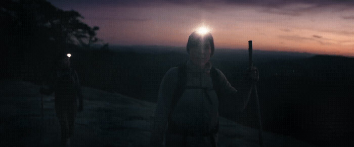 two people standing on top of a mountain at night