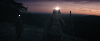 two people standing on top of a mountain at night